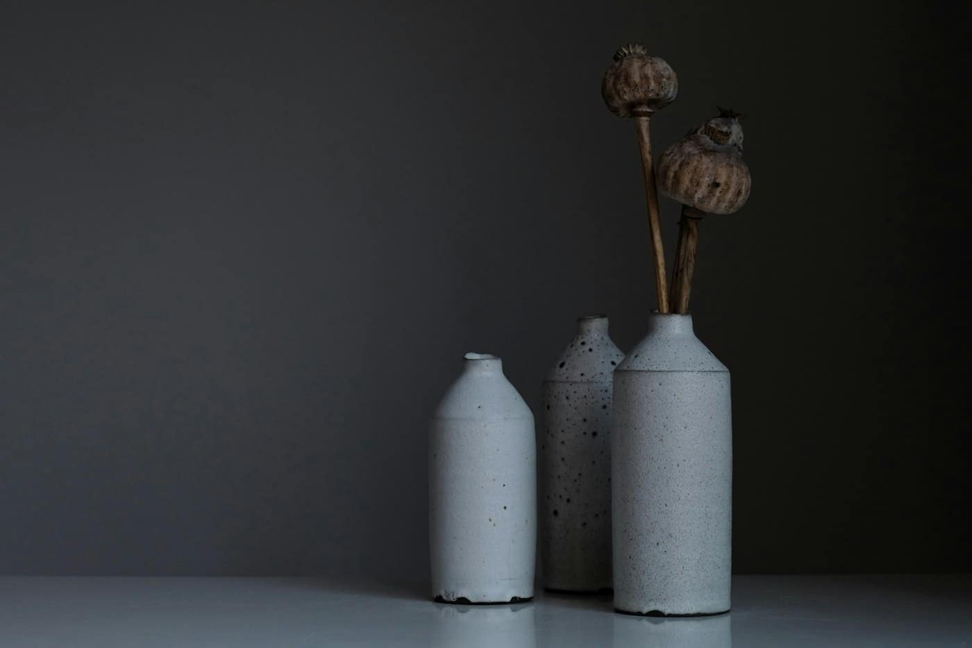 Três vasos de cerâmica clara com flores secas